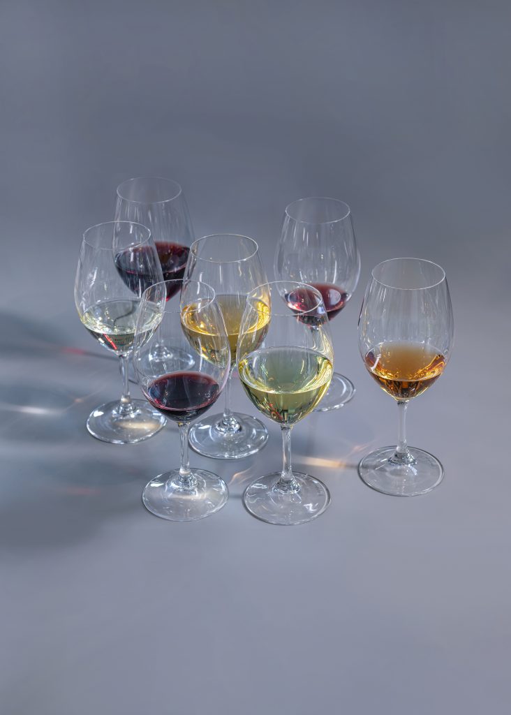 Vinglas fyllda med rött vin och vitt vin mot en gråblå bakgrund